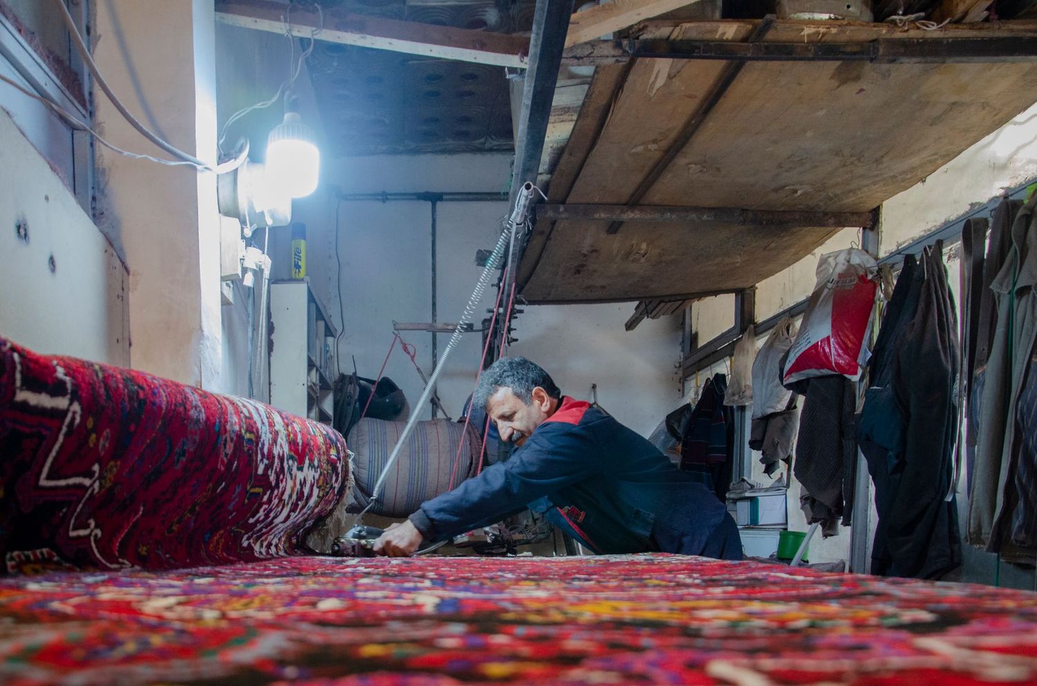 Artisan penché sur un tapis d'Orient pendant une réparation en atelier